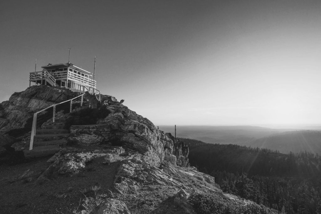 Black & white photograph of a fire tower on a mountain summit
